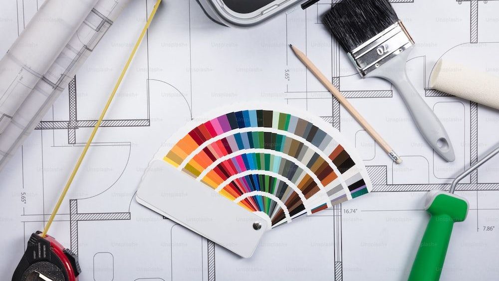 Vista de alto ángulo de la guía de color Muestra en planos con rodillo de pintura y pincel